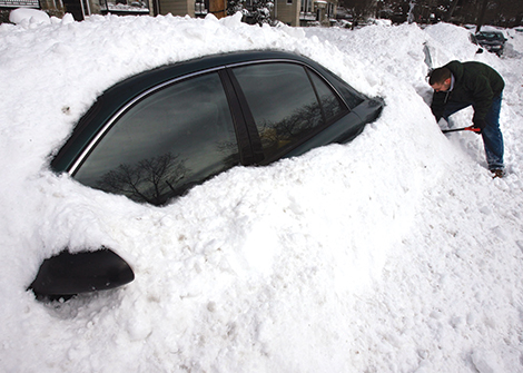 A man in Cleveland must dig his car out of a pile of snow. 