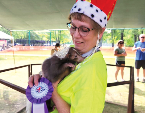 Deborah Cipriani holding a pet skunk and a purple ribbon
