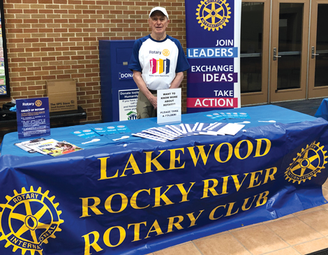 Harlan Radford standing behind a table for the Lakewood Rocky River Rotary Club